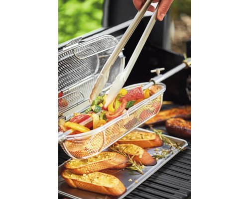 Groenten in grillmand met grilltang en baguette op een schaal