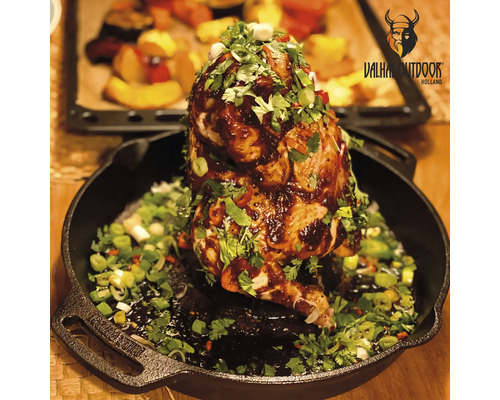 Gegrilde kip in een gietijzeren pan met kruiden en groenten