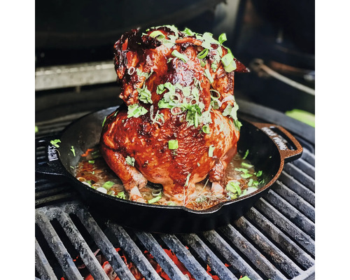 Gegrilde kip in een braadpan met kruiden op een grill.
