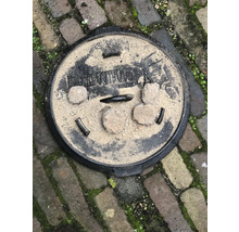 Rond metalen putdeksel op straatstenen