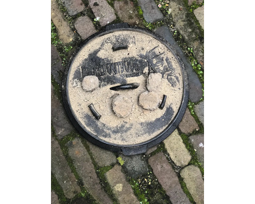 Rond metalen putdeksel op straatstenen