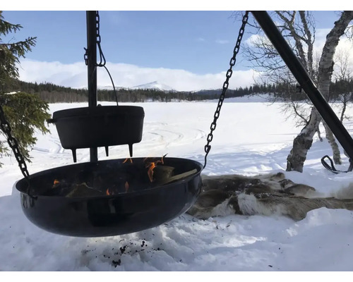 Vuurschaal met kookpot boven een open vuur in een besneeuwd landschap