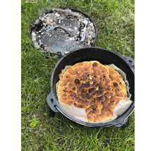Brood in een Dutch oven met afgenomen deksel op gras.