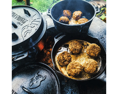 Gietijzeren potten en pannen met eten op een vuurplaats