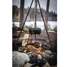 Bovenaanzicht van een Dutch oven boven een kampvuur op een driepoot met grillrooster in de buitenlucht.