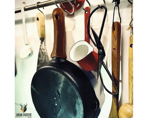 Keukengerei hangt aan een stang, inclusief braadpan, schaar en soeplepel.