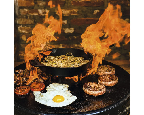 Flammende bakplaat met gerechten zoals burgers, spiegelei, groenten en noodles in een pan
