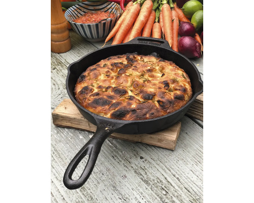 Gietijzeren pan met brood op houten tafel met groenten