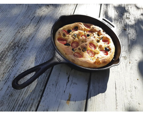 Focaccia met tomaten en olijven in een gietijzeren pan
