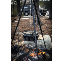 Kampvuur met Dutch oven boven een grillrooster, hangend aan een driepoot