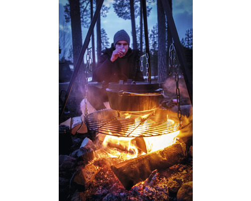 Kampvuurplaats met driepoot, grillrooster, Dutch oven en persoon in de natuur