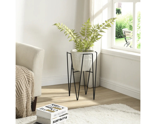 Kamerbeeld met plant in een pot op een metalen standaard.