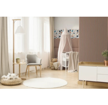 Lichte kinderkamer met babybed, stoel, commode en decoratieve elementen.