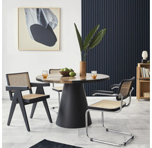Eetkamer met ronde houten tafel, zwarte stoelframes en kunstwerk aan de muur.