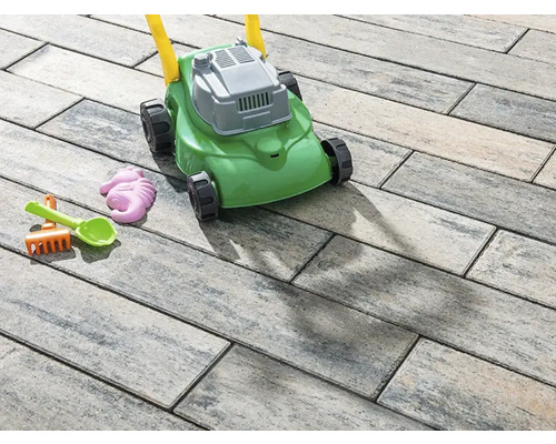 Speelgoed grasmaaier en zandspeelgoed op straatstenen