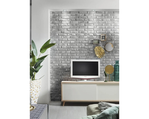 Woonkamer met grijze bakstenen muur, televisie en wit dressoir