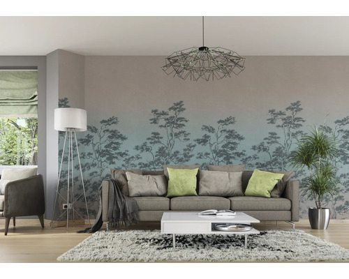 Woonkamer met bank, salontafel, staande lamp, kamerplant en fotobehang met boommotief.