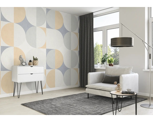 Woonkamer met geometrisch behang, fauteuil, vloerkleed en commode