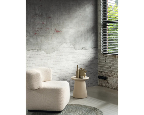 Woonkamer met fauteuil, bijzettafel en decoratieve vazen tegen een muur met baksteenmotief