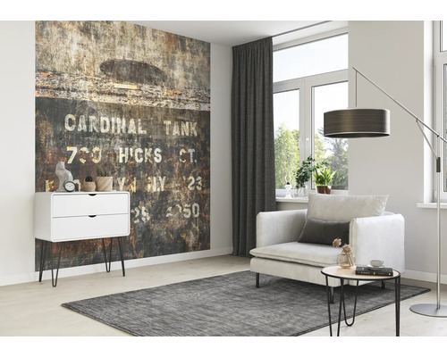 Woonkamer met patroonbehang, fauteuil, staande lamp en commode