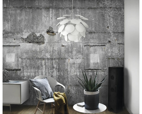 Lichte woonkamer met betonnen muur, stoel, commode, kamerplant, luidspreker en een ronde hanglamp