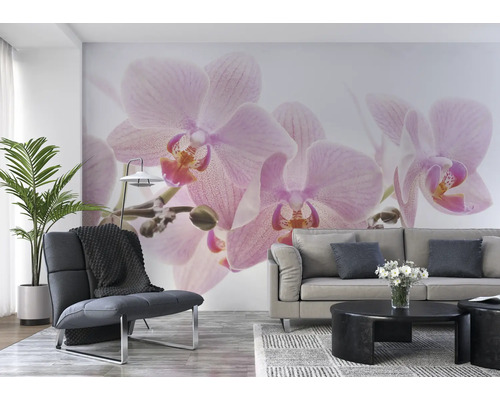 Woonkamer met muurschildering met orchideeën, fauteuil, bank en tafel.