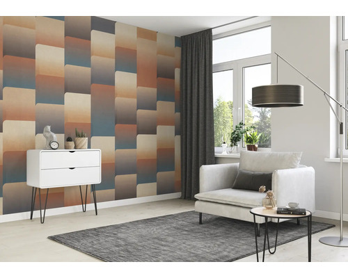 Woonkamer met gedessineerd behang, fauteuil, bijzettafel, vloerlamp en commode