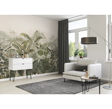 Woonkamer met junglebehang, fauteuil, staande lamp en commode