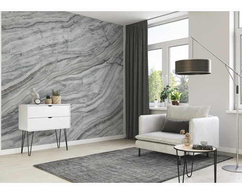 Woonkamer met marmeren behang, fauteuil, vloerkleed en ladekast