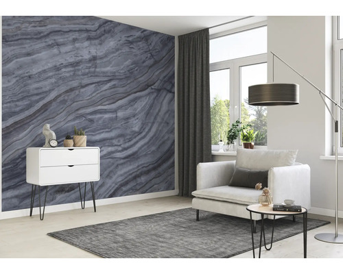 Woonkamer met marmer behang, fauteuil, vloerlamp, tapijt en ladekast