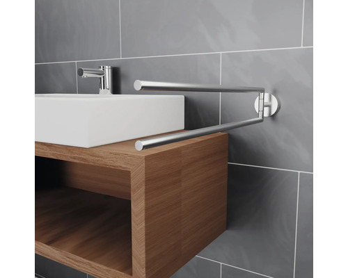 Wastafel met draaibare handdoekhouder aan betegelde muur