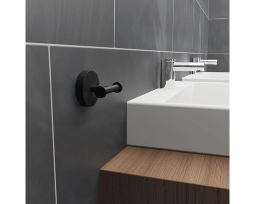 Badkamer met wastafel, kraan en een zwarte handdoekhaak