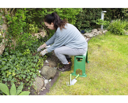 Een vrouw werkt in de tuin met een tuinbank en tuingereedschap.