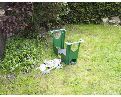 Tuinscene met een tuinkruk, een schop, een hark en tuinhandschoenen op een gazon