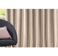Beige gordijn naast een fauteuil met kussen.