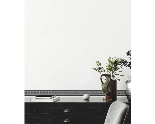 Decoratieve border met Grieks meandermotief op een muur boven een bureau.