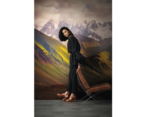 Decoratief bergbehang met een vrouw die tegen een Barcelona-stoel leunt