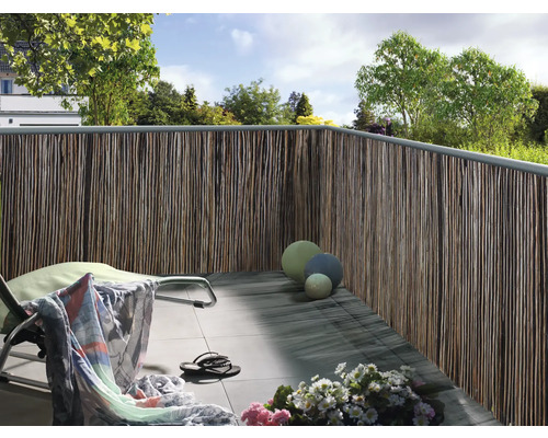 Balkon met privacyscherm van natuurlijke materialen, ligstoel en decoratie