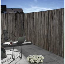 Schutting van natuurlijk materiaal naast een tuintafel met laptop buiten.