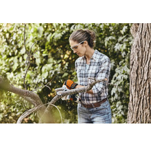 Vrouw zaagt een tak in de tuin met een accuservozaag