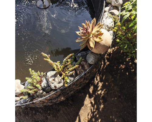 Close-up van een tuinvijver met een omheining van schanskorven, stenen en planten
