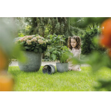 Tuinscene met meisje, plant en plantenbakken op gazon