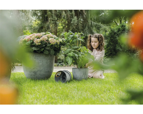 Tuinscene met meisje, plant en plantenbakken op gazon
