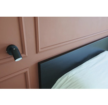 Wandlamp naast een bed met hoofdeinde.