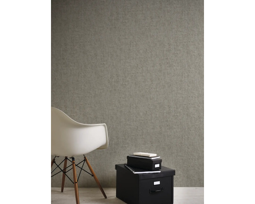 Close-up van een gestructureerd behang in een kamer met een stoel en opbergdozen.