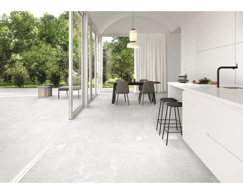 Lichte, betegelde woonkamer met eethoek en toegang tot het terras.