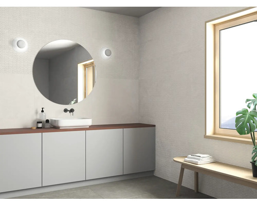 Lichte badkamer met wastafel, spiegel en bank onder een raam.