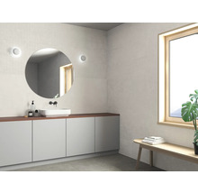 Moderne badkamer met ronde spiegel, wastafel en raam voor een heldere sfeer