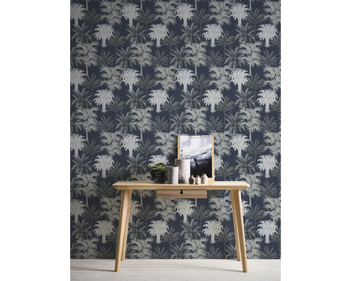 Kamerweergave met een wandbehang met palmmotief achter een houten tafel