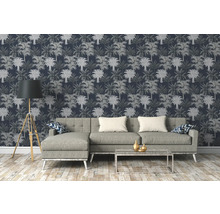 Woonkamer met bank, staande lamp en behang met palmmotief